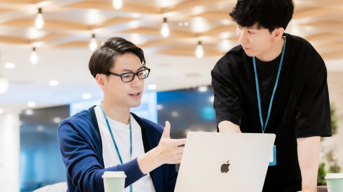 ノートパソコンを見ながら打ち合わせをしている二人の男性