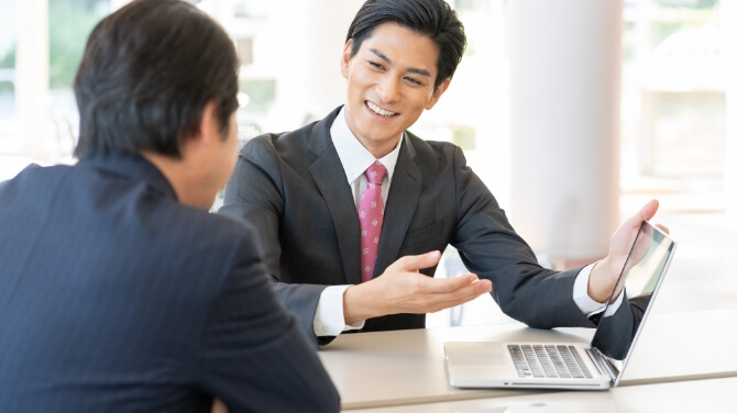 ノートパソコンを見ながら打ち合わせをしている二人の男性