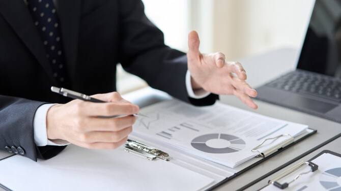 デスクの上に資料を置いて打ち合わせをしている様子